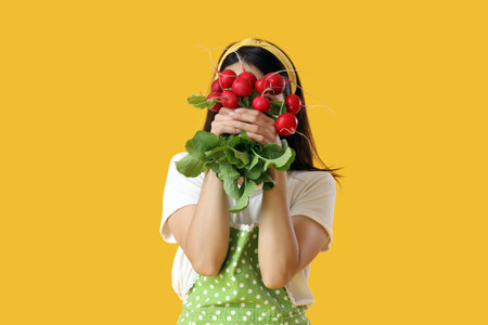 Young housewife with ripe radish on yellow backgroundの写真素材