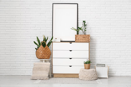 Interior of room with commode, blank frame and green plants in wicker basketsの写真素材