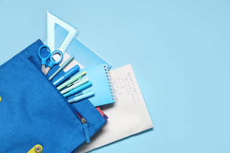 Backpack with different school stationery on blue background, closeup