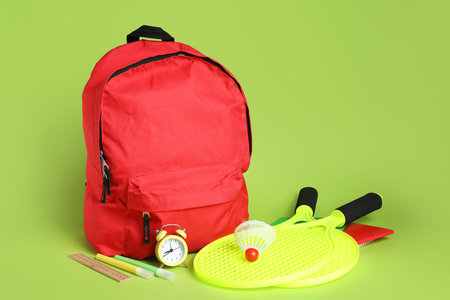 Backpack, school supplies and sports equipment on green backgroundの写真素材
