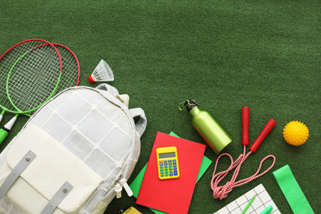 Composition with backpack, school supplies and sports equipment on green grass backgroundの写真素材