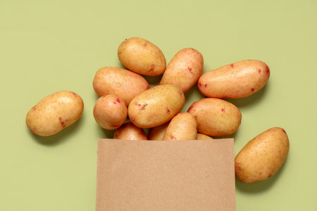Paper bag with raw baby potatoes on green backgroundの写真素材