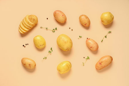 Raw baby potatoes with thyme and peppercorns on beige backgroundの写真素材