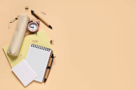 Composition with different school stationery and alarm clock on beige background