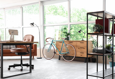 Modern bicycle near chest of drawers in home office interiorの写真素材