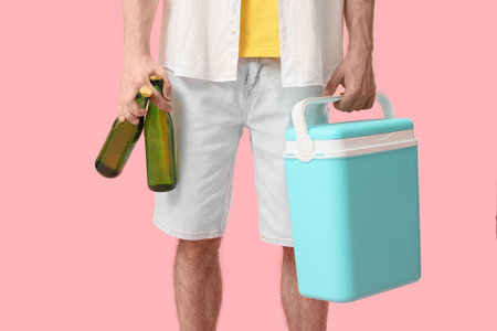Young man with portable refrigerator and bottles of cold beer on pink background, closeupの写真素材
