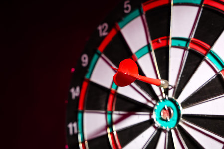 Board with dart on dark background, closeupの写真素材