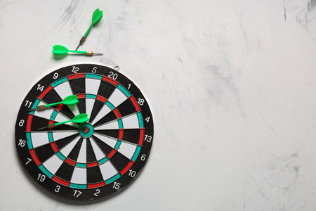 Board with darts on light background