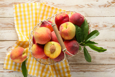 Basket of fresh peaches on light wooden background, top viewの写真素材