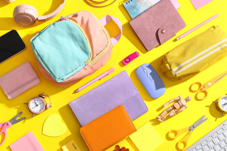Composition with modern mobile phone and school supplies on yellow backgroundの写真素材