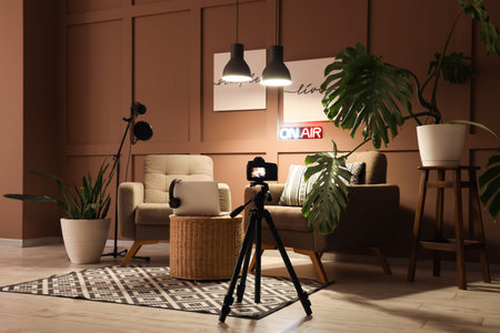 Interior of podcaster's studio with armchairs, plants and glowing lamps