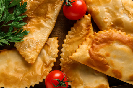 Board with tasty chebureks, fresh tomatoes and parsley, closeupの写真素材