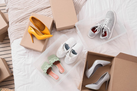 Container and boxes with different shoes on bed, top viewの写真素材