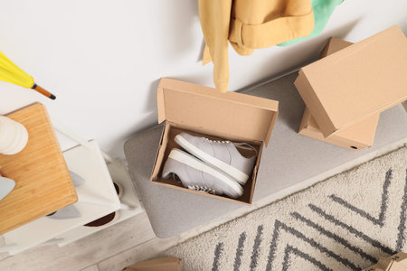 Shoe boxes with sneakers on soft bench in wardrobe, top view