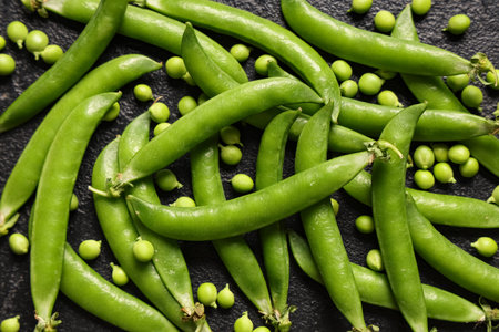 Composition with fresh green peas on black grunge background, closeup
