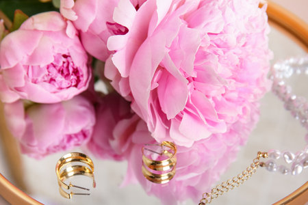 Jewelery and beautiful peony flowers on mirror as background, closeupの写真素材