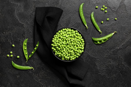 Bowl with fresh green peas on black grunge backgroundの写真素材