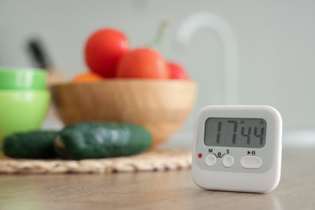 Kitchen timer and vegetables on table in room, closeupの写真素材