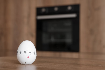 Kitchen timer on table against oven in room, closeup