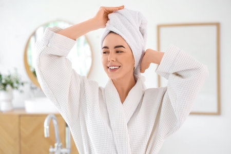 Young woman in waffle robe after shower at homeの写真素材