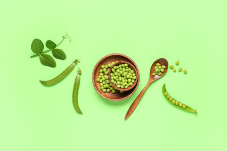 Wooden bowls and spoon with fresh green peas on color backgroundの写真素材