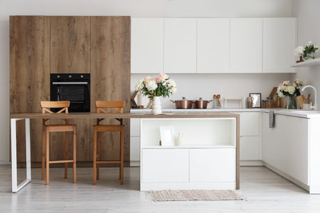 Interior of stylish kitchen with island table and beautiful peonies