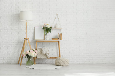 Interior of stylish room with standard lamp, table and beautiful peoniesの写真素材