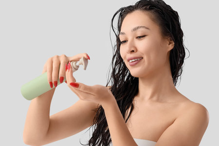 Pretty young Asian woman with shampoo on white backgroundの写真素材