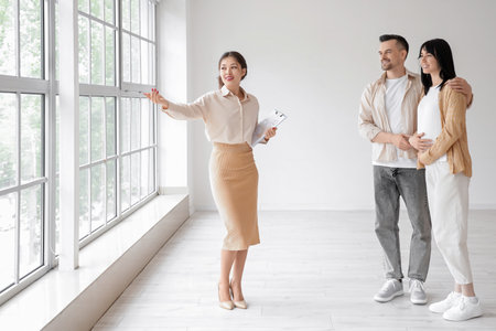 Female Asian real estate agent showing new house to pregnant coupleの写真素材
