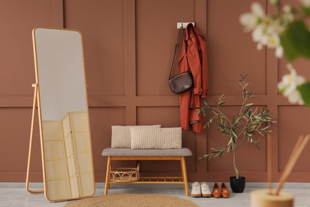 Interior of stylish hallway with soft bench, mirror and coatの写真素材