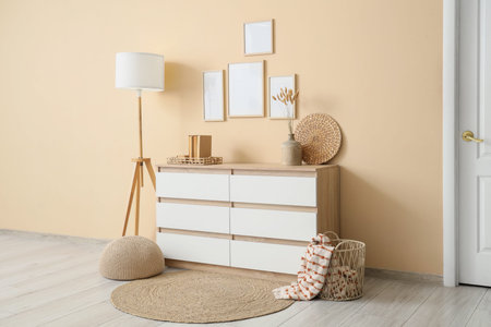 Interior of stylish modern room with chest of drawers, floor lamp and blank photo frames
