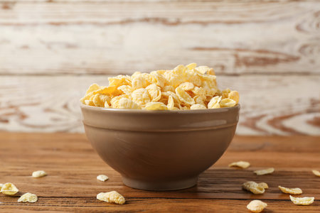 Bowl of tasty cornflakes on wooden background