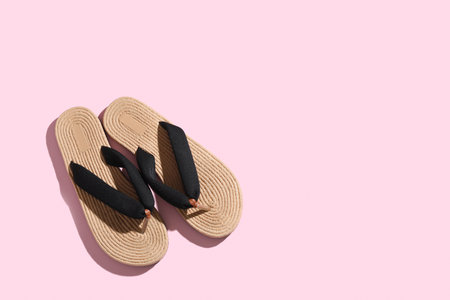 Stylish wicker flip-flops on pink background