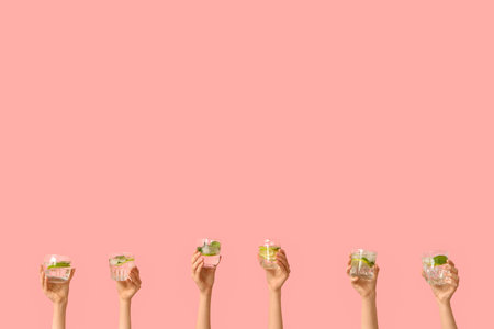 Female hands holding different glasses of fresh mojito on pink backgroundの写真素材