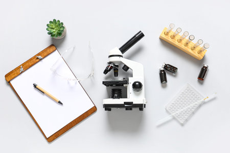 Modern microscope, clipboard and test tubes with blood samples on white background