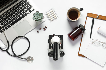 Modern microscope, cup of coffee, pills and laptop on white backgroundの写真素材