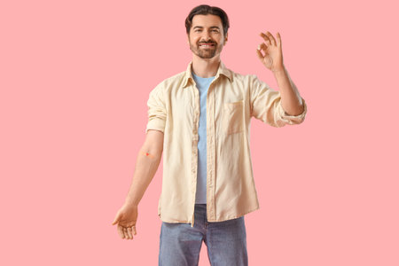 Male blood donor with medical patch showing OK on pink background