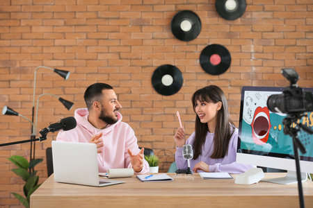 Young couple recording podcast at table in studio