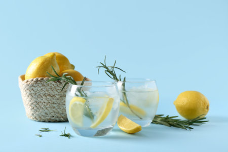 Glasses of fresh lemonade with rosemary and lemons on blue backgroundの写真素材
