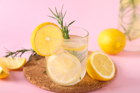 Glass of fresh lemonade with rosemary and lemons on pink backgroundの写真素材