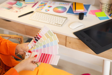 Female web designer with color palettes at table in office, closeup