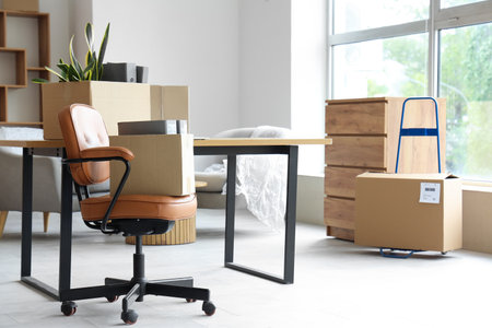 Packed boxes with belongings and furniture in new office on moving dayの写真素材
