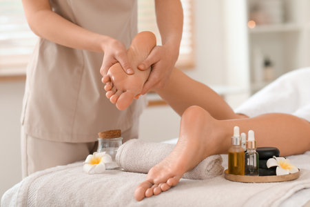 Female therapist massaging woman's foot in spa salon, closeupの写真素材