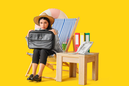 Sad businesswoman with briefcase in deck chair on yellow background. Summer vacation conceptの写真素材