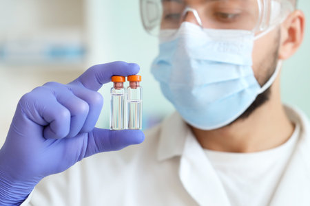 Male scientist with ampules in laboratory, closeup