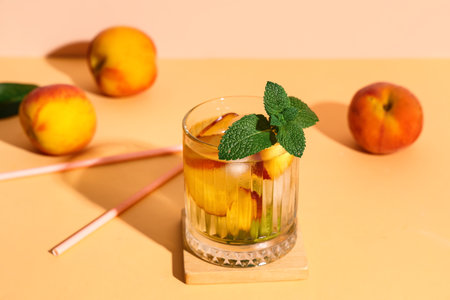 Glass of fresh peach lemonade with mint and fruits on orange table against beige backgroundの写真素材