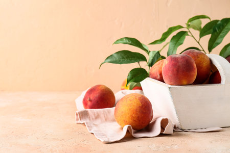 White basket with sweet ripe peaches and leaves on beige backgroundの写真素材