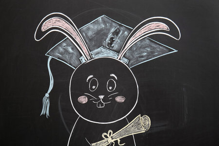 Drawn bunny with graduation hat and diploma on blackboardの写真素材