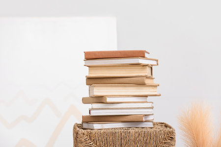 Stack of books on wicker basket and pampas grass near white wallの写真素材