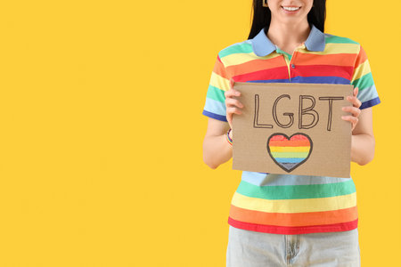 Young woman holding placard with the word LGBT on yellow background, closeupの写真素材
